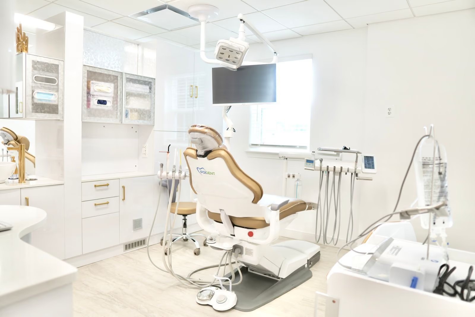 A treatment room with the dental chair, overhead light and chairside monitor