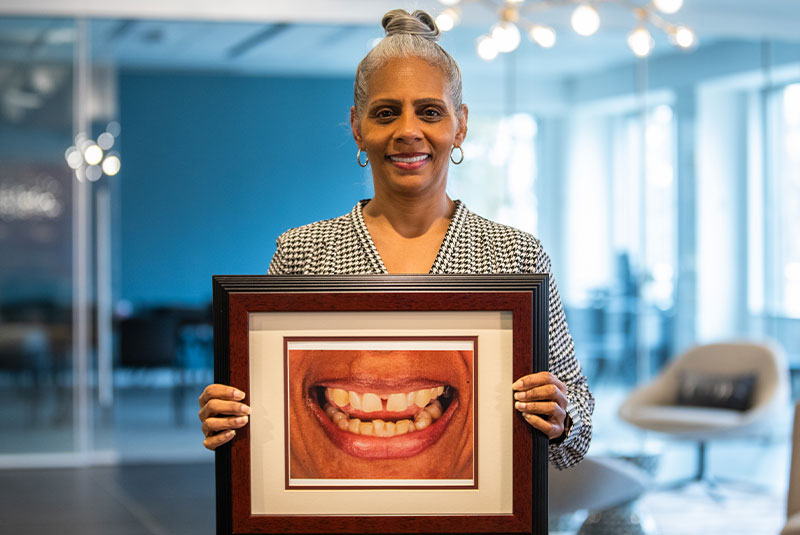 Yolanda holding a framed photograph of her smile before treatment