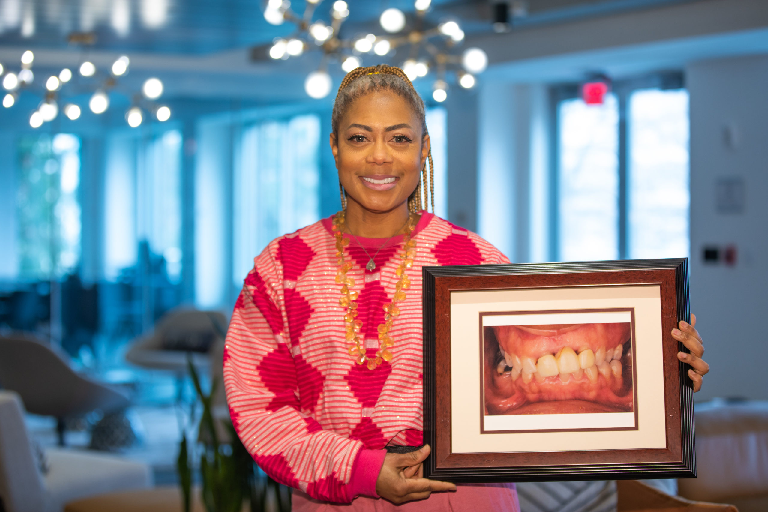 A patient holding a framed photograph of her smile before treatment