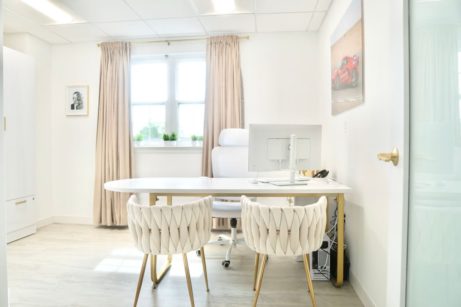A consultation room with a round table, two upholstered chairs and a monitor