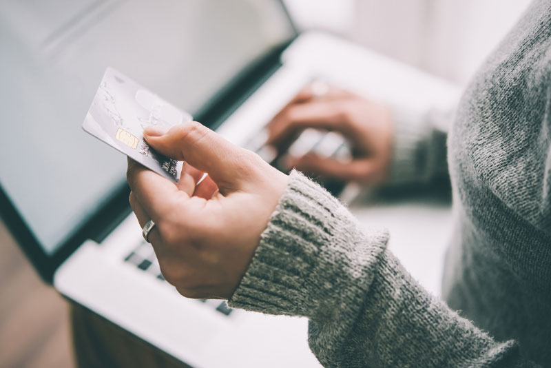 A patient holding a credit card while paying at a laptop