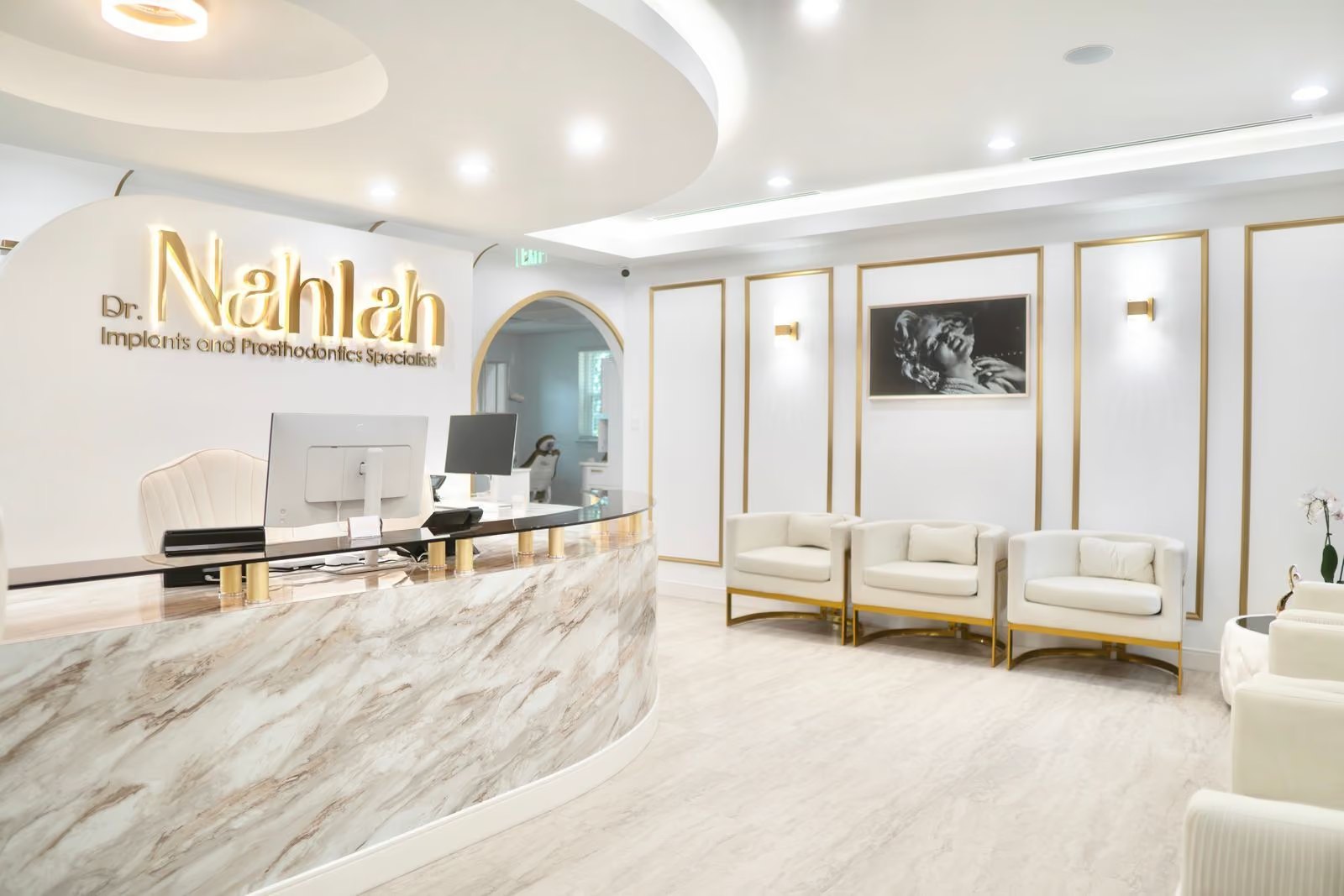 The reception desk, with the Dr. Nahlah wordmark above a marble counter and cream and gold waiting chairs